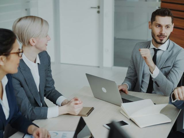 Executives in formal dress meeting around a boardroom table